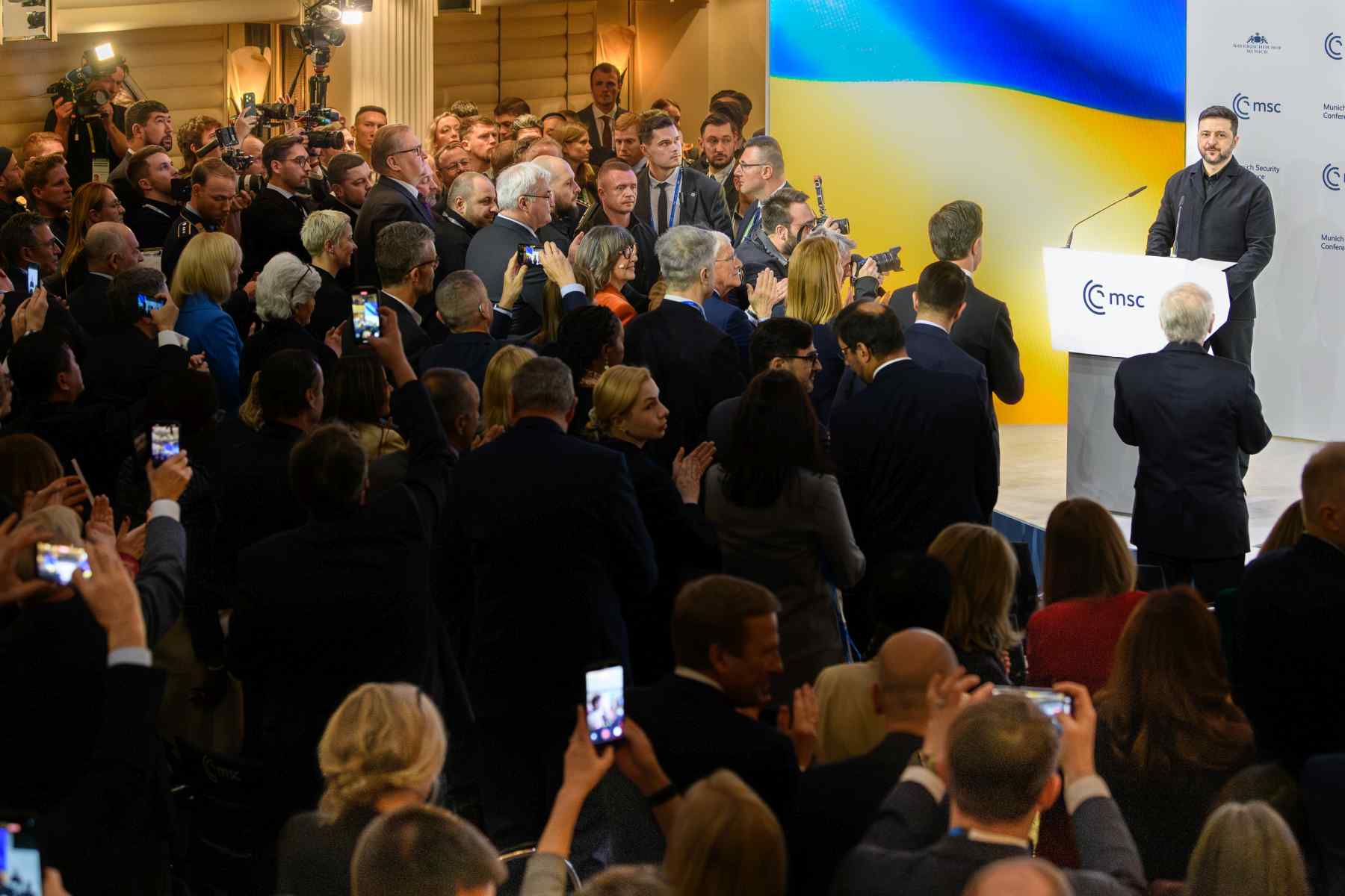 Wolodymyr Selenskyj auf der Bühne der Münchner Sicherheitskonferenz, vor ihm stehende Teilnehmer applaudieren.